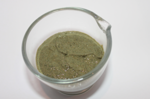 A bowl of green stuff is sitting on the table.