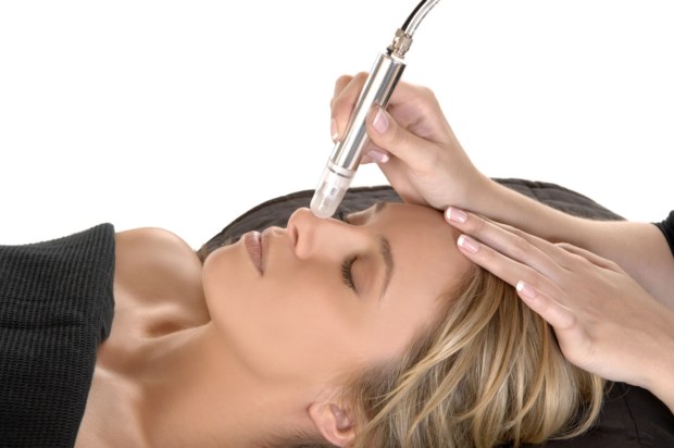 A woman getting her face cleaned with an electric device.