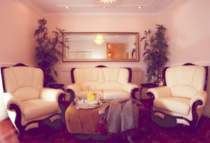 A living room with white furniture and a mirror.