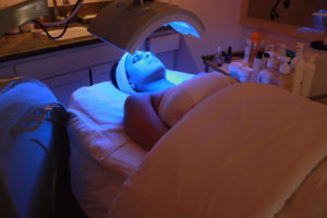 A person under an led light on top of a bed.