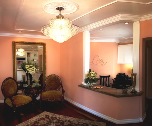 A living room with pink walls and a chandelier.
