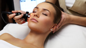 A woman getting her face cleaned by an esthetician.