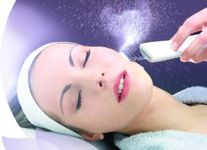 A woman getting her face cleaned with an electric device.