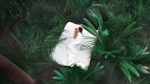 A person laying in the grass with a sheet